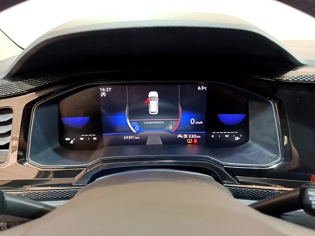 Vue rapprochée du tableau de bord numérique du Volkswagen Taigo noir, affichant la consommation et la vitesse à 0 km/h.