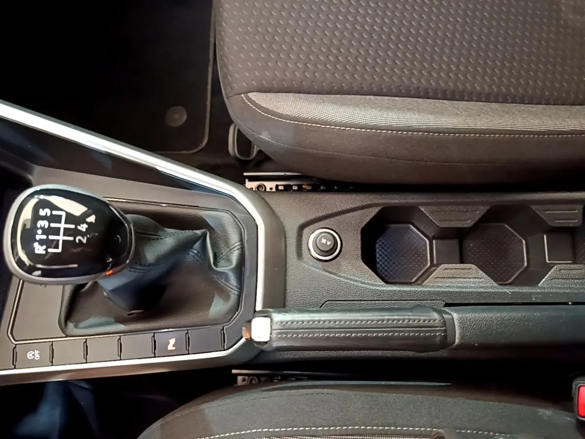 Vue rapprochée de la console centrale du Volkswagen Taigo noir 2023, avec levier de vitesse manuel et frein à main cuir.