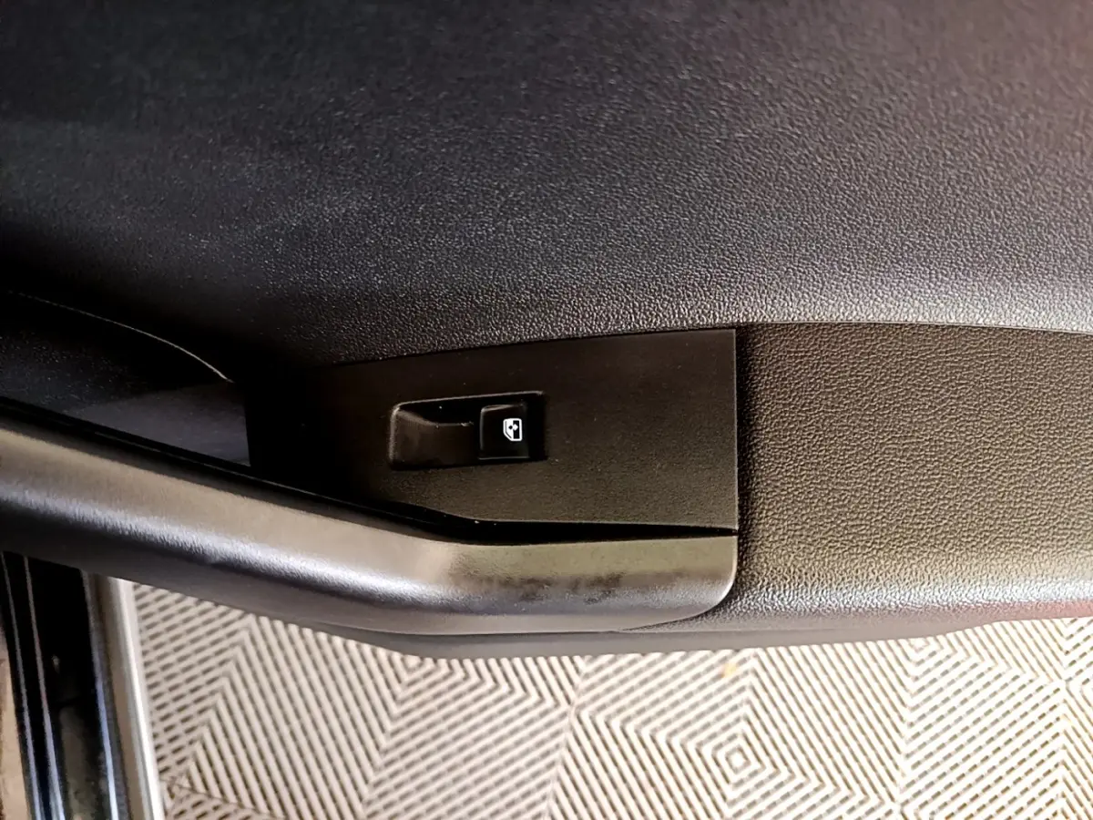 Détail de la commande de lève-vitre électrique sur la porte avant gauche d’un Volkswagen Taigo noir.