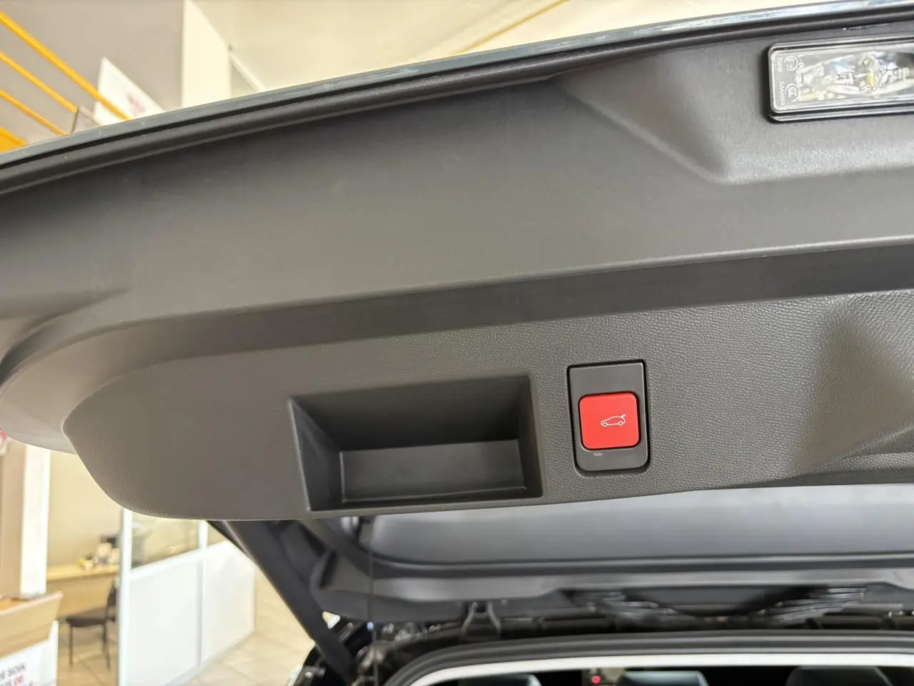 Gros plan sur le bouton de fermeture électrique du hayon du Citroën C5 Aircross vert, intérieur du coffre visible.