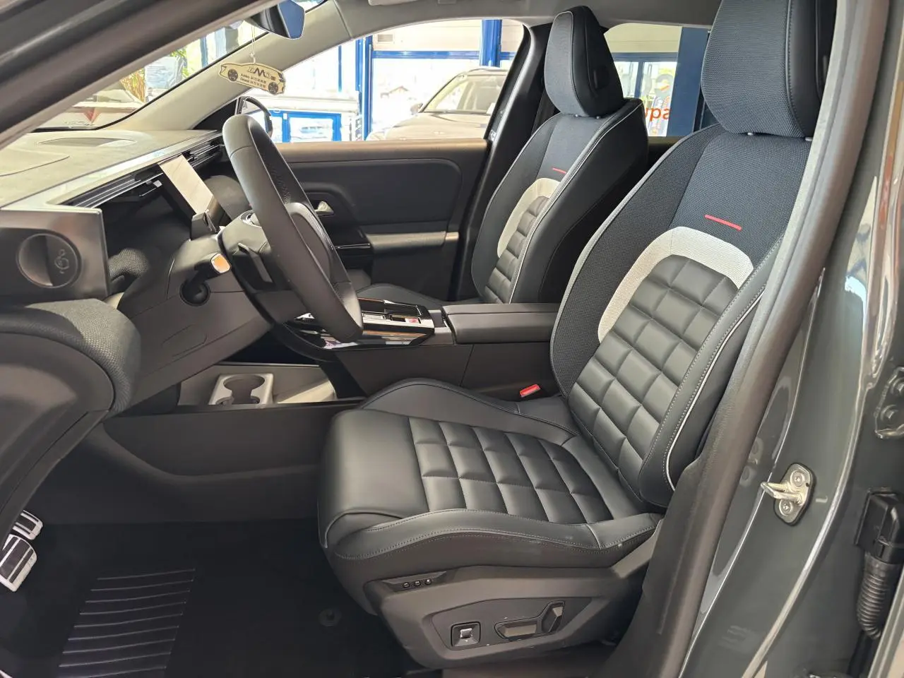 Vue intérieure côté conducteur du Citroën C5 Aircross vert, sièges cuir noir avec inserts gris et rouge, volant multifonctions.