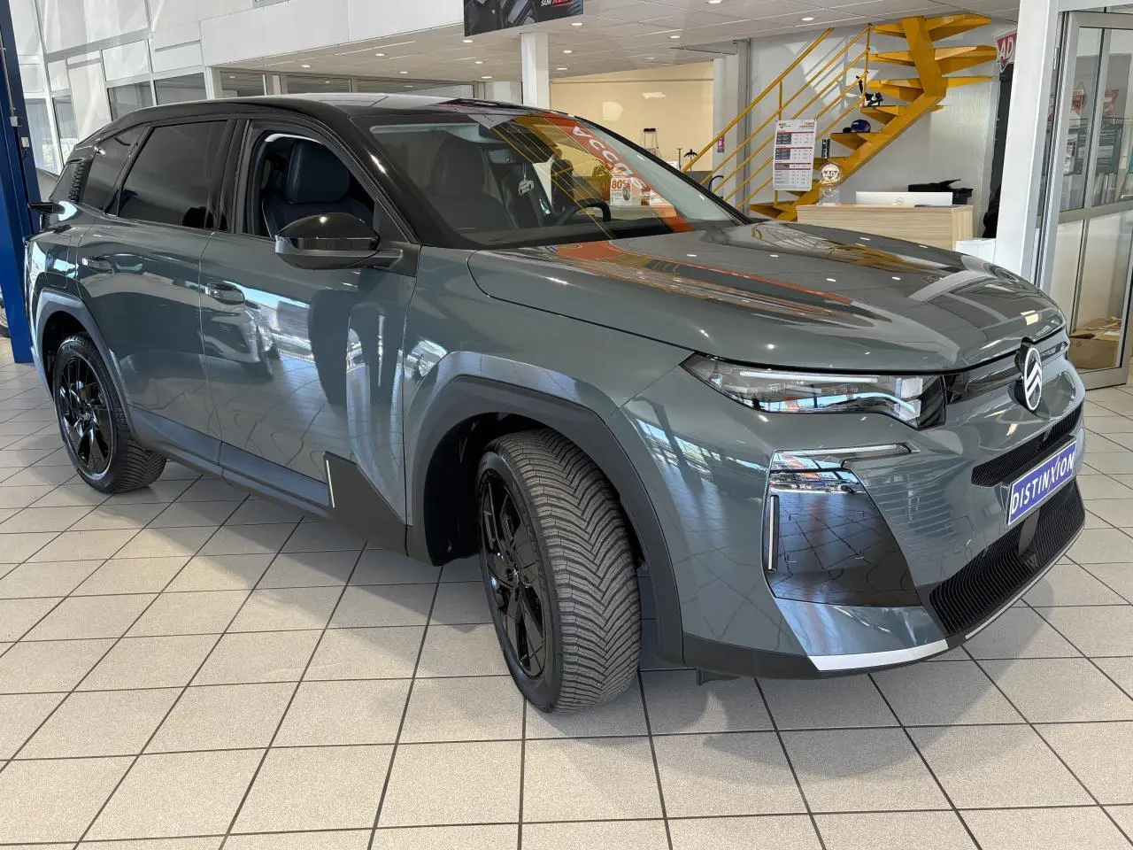 Citroën C5 Aircross 2026 vert, vue 3/4 avant droit en showroom avec jantes alliage noires.