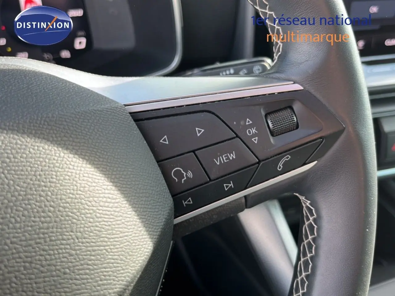 Gros plan sur les commandes multifonctions à droite du volant en cuir noir du SEAT Leon 2025 blanc neige.