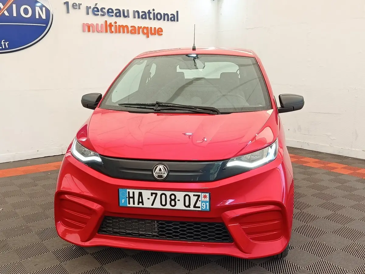 Vue avant d'une Aixam Ambition 0.5 City Pack rouge 2024 avec rétroviseur côté conducteur visible.