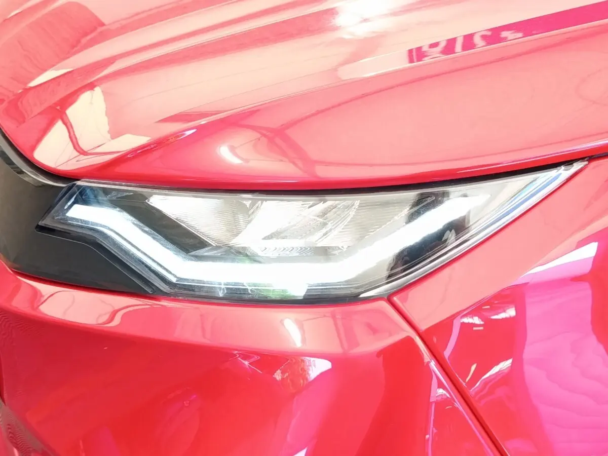 Gros plan sur le phare avant droit d'une Aixam Ambition 0.5 City Pack rouge 2024 avec éclairage LED distinctif.