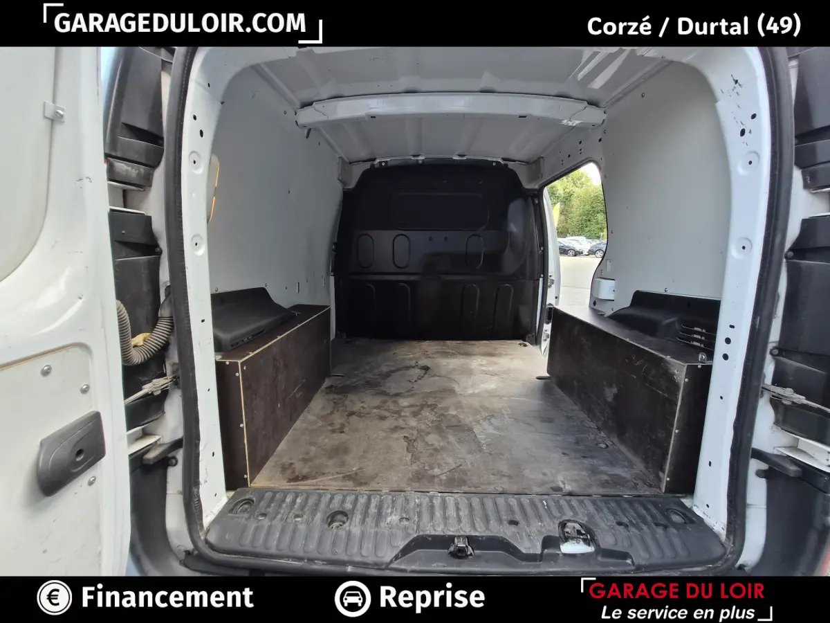 Vue intérieure arrière du Renault Kangoo blanc montrant l'espace de chargement vide avec cloison noire pleine.