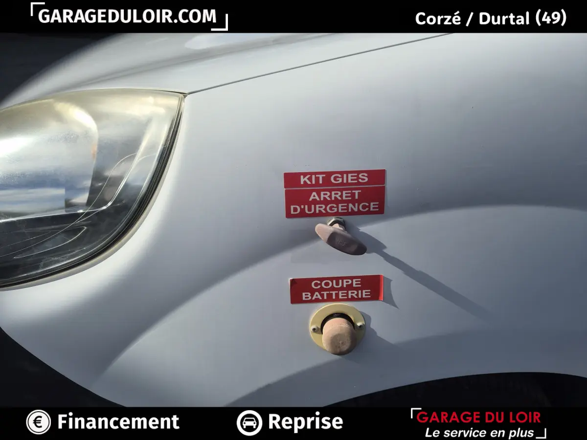 Vue rapprochée de l'aile avant gauche blanche du Renault Kangoo avec interrupteurs d'arrêt d'urgence et coupe batterie.