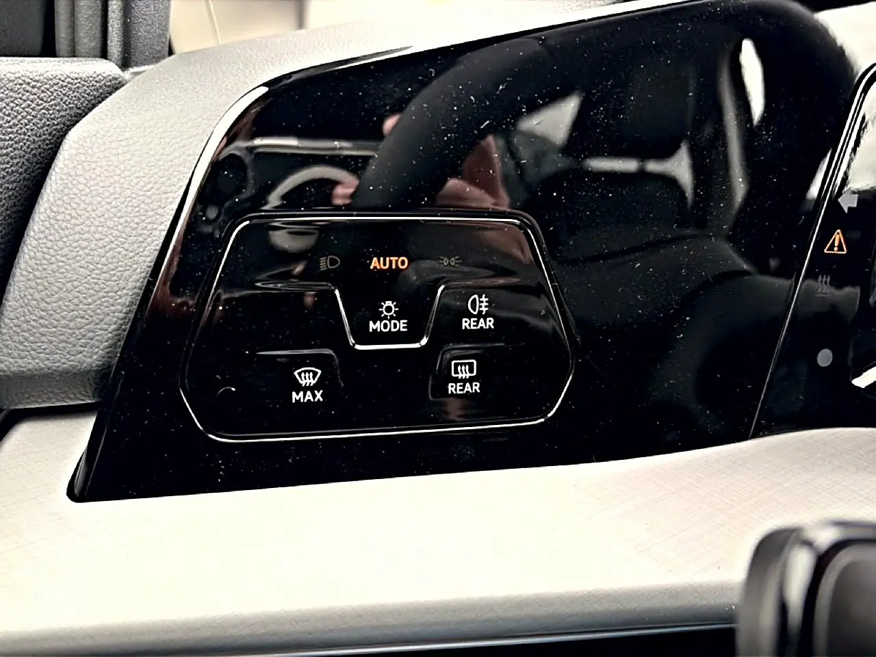 Gros plan sur les commandes de phares automatiques et dégivrage sur le tableau de bord noir de la Volkswagen Golf 2026.
