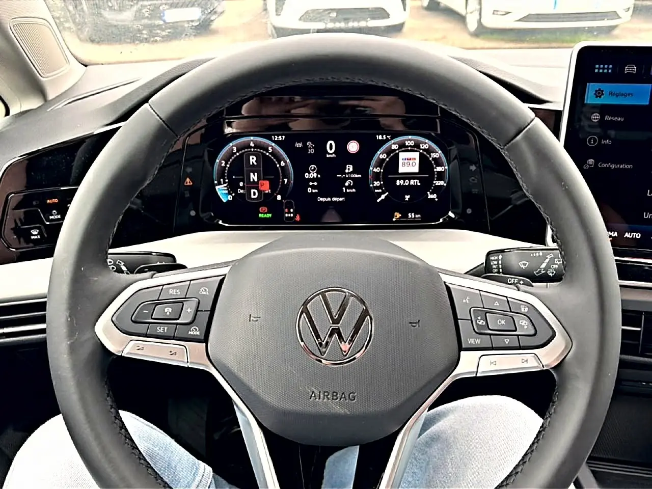 Vue centrée sur le volant noir et le tableau de bord numérique de la Volkswagen Golf 2026, affichage clair et moderne.