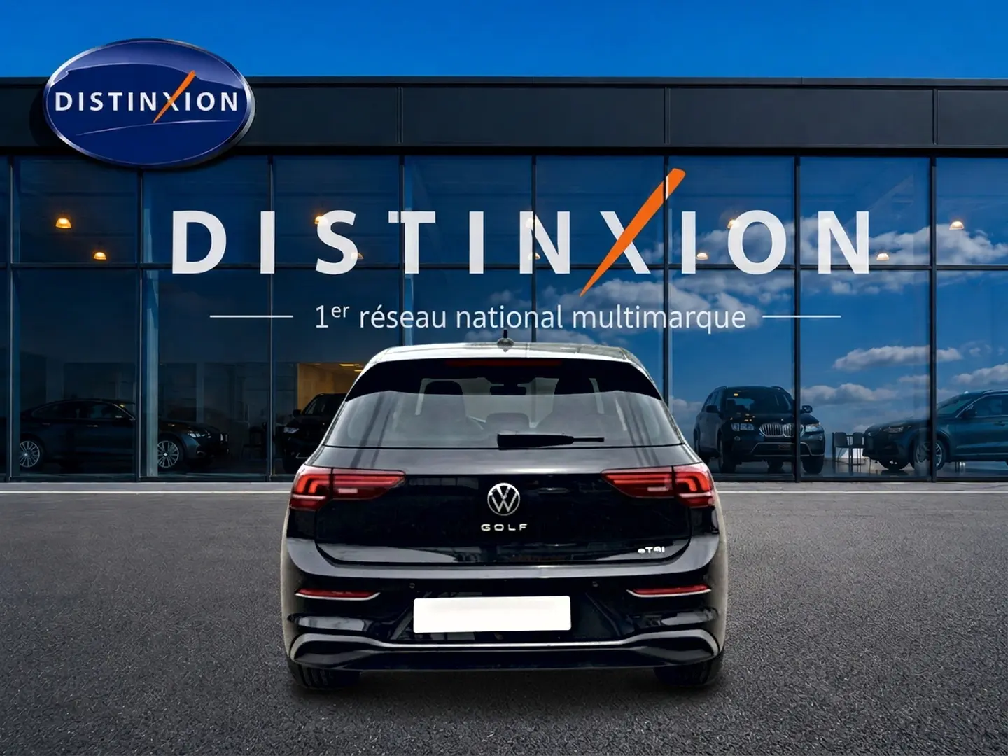 Vue arrière d'une Volkswagen Golf noire 2026 garée devant une vitrine avec logo Distinxion.