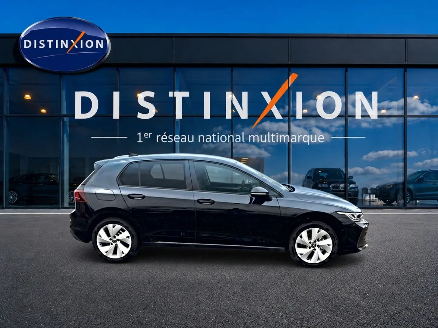 Profil côté gauche d'une Volkswagen Golf noire 2026 garée devant une vitrine avec logo Distinxion.