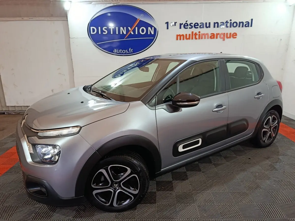 Citroën C3 gris clair vue 3/4 avant droit, avec protections latérales noires et jantes alliage distinctives.