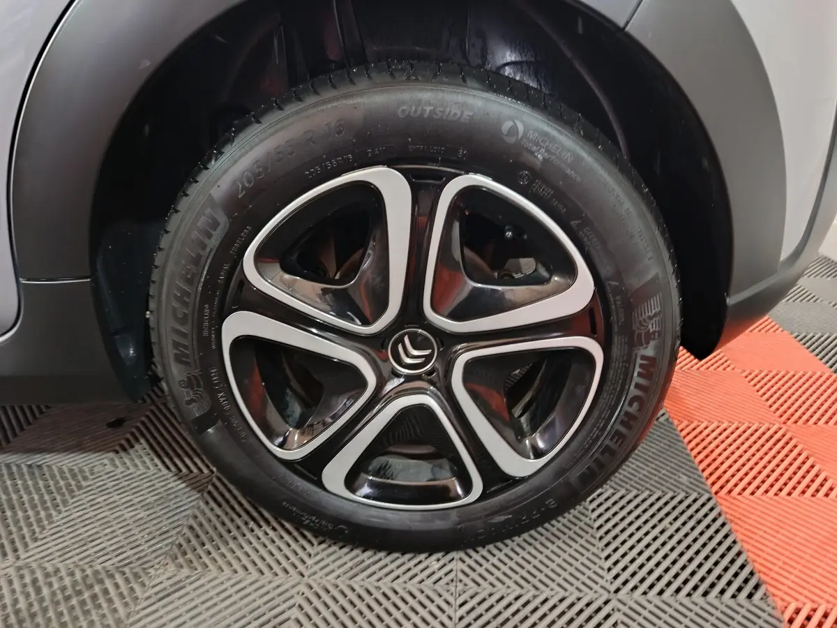 Gros plan sur la roue avant droite d'une Citroën C3 gris clair avec jante alliage noire et argentée.