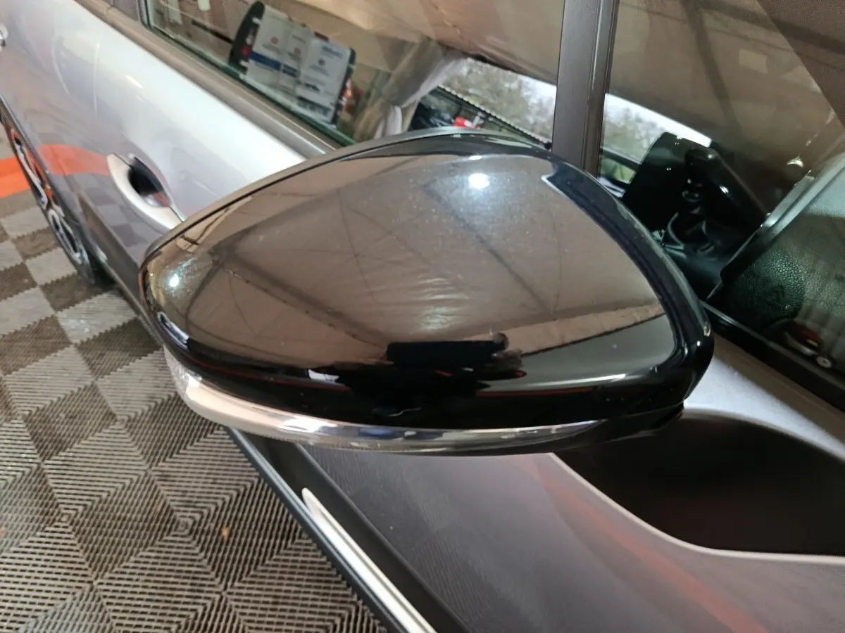 Rétroviseur extérieur noir côté conducteur d'une Citroën C3 gris clair vue en gros plan, avec poignée de porte visible.