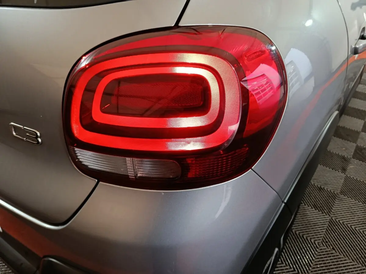 Gros plan sur le feu arrière droit rouge et la carrosserie gris clair d'une Citroën C3 2024 côté arrière.