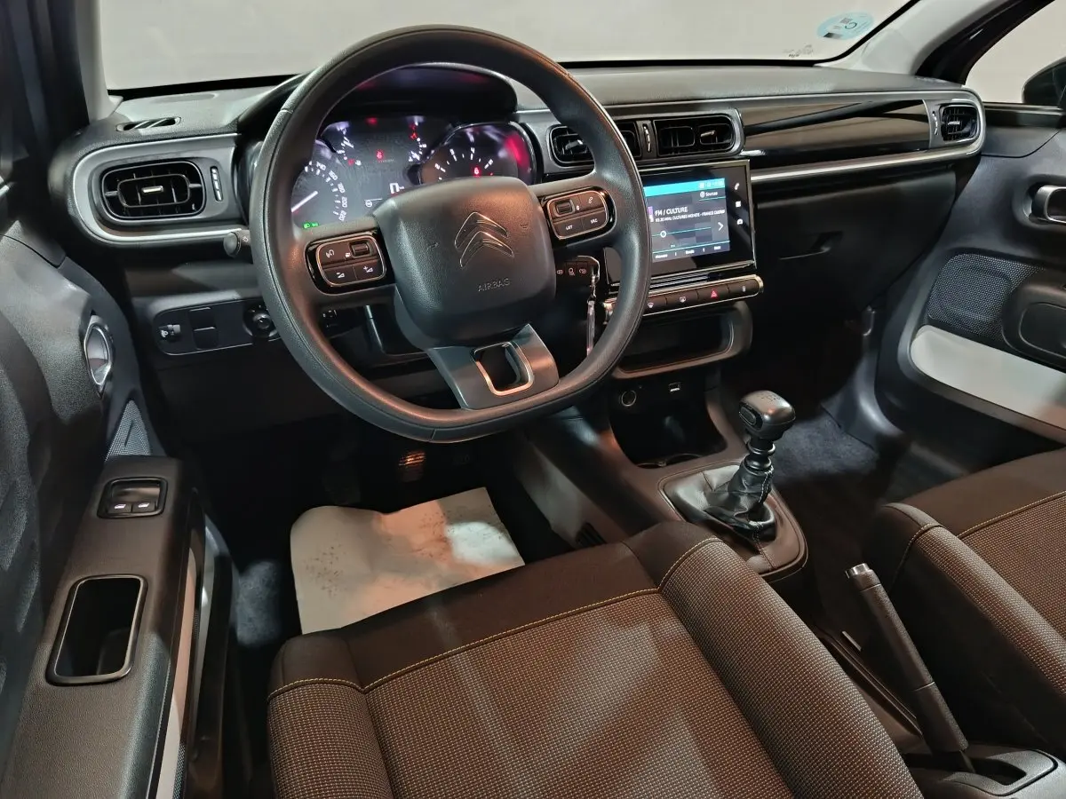 Vue intérieure côté conducteur de la Citroën C3 2024, tableau de bord noir avec écran tactile et volant multifonctions.
