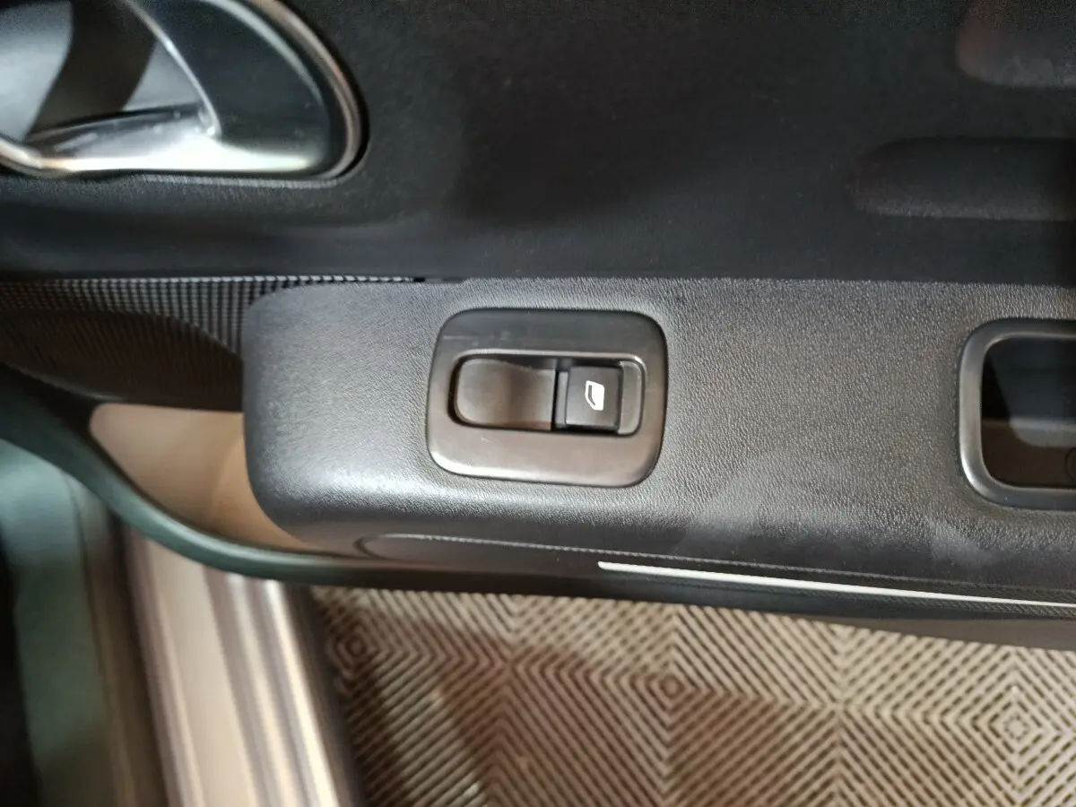 Gros plan sur la commande de lève-vitre côté conducteur de la Citroën C3 gris clair, intérieur noir.