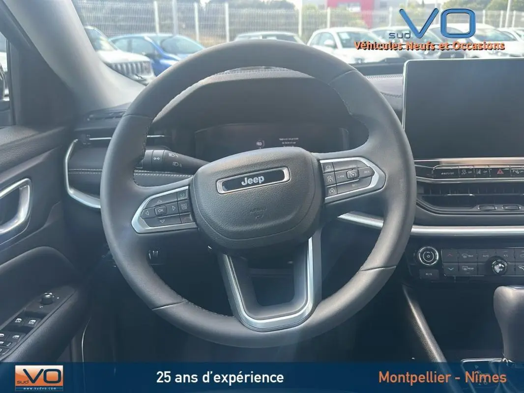 Vue intérieure centrée sur le volant Jeep du Compass 2024, avec tableau de bord et écran tactile visibles.