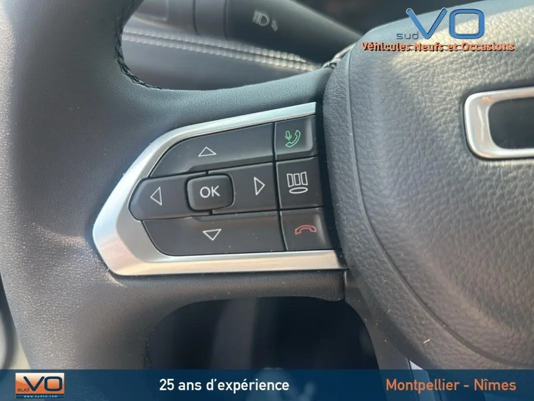 Gros plan sur les commandes du volant du Jeep Compass blanc 2024, version e-Hybrid Altitude avec pack hiver.