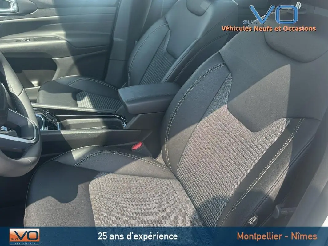 Gros plan sur les sièges avant noirs du Jeep Compass e-Hybrid 2024, mettant en valeur les surpiqûres et l'accoudoir central.