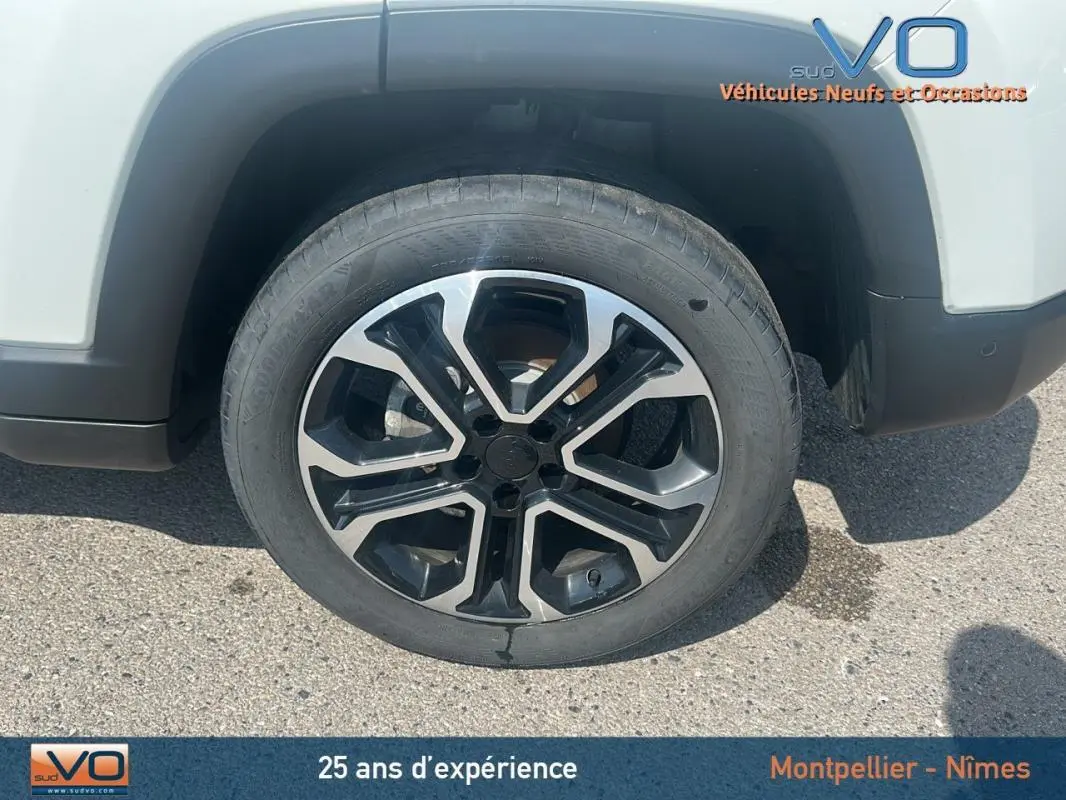 Gros plan sur la jante 17 pouces noire et argent du côté gauche d'un Jeep Compass blanc 2024 avec roue de secours visible.