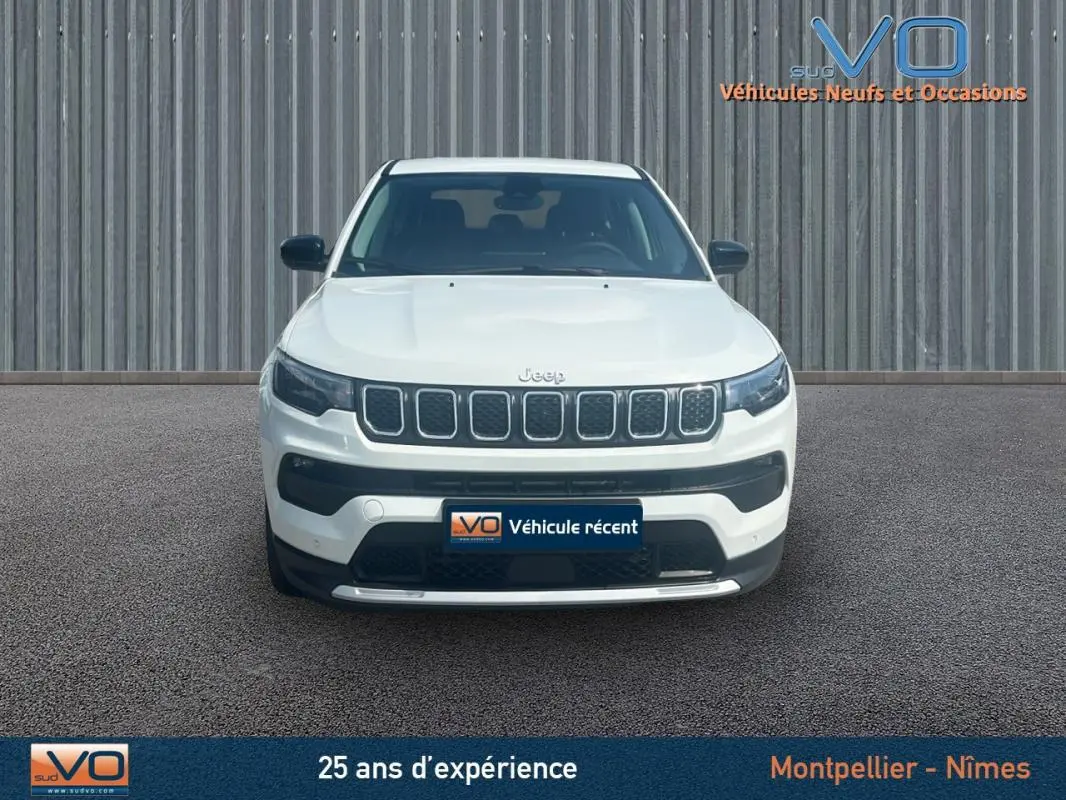 Vue frontale d'un Jeep Compass blanc 2024 avec calandre caractéristique et pare-chocs noir contrastant.