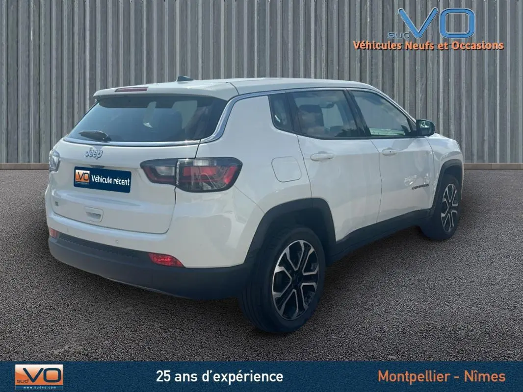 Vue 3/4 arrière droite d'un Jeep Compass blanc 2024 avec jantes 17 pouces et roue de secours visible sur le hayon.