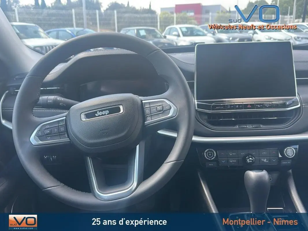 Intérieur du Jeep Compass 2024 montrant le volant et l'écran tactile central, avec commandes au volant visibles.