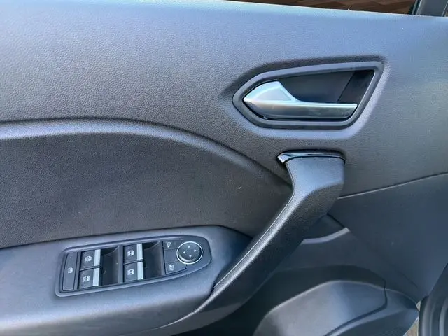Gros plan sur la porte intérieure côté gauche du Renault Captur 2024 gris Cassiopée avec commandes de vitres et poignée argentée.