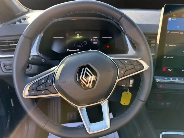 Gros plan sur le volant noir du Renault Captur 2024 avec commandes intégrées et écran numérique en arrière-plan.