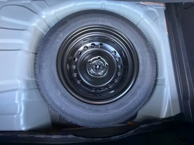 Roue de secours noire vue de dessus dans le coffre du Renault Captur 2024 gris cassiopée toit noir.