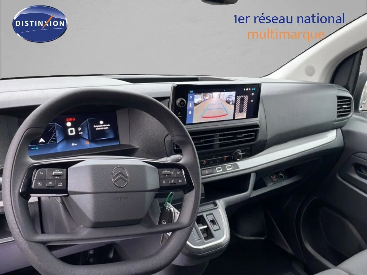 Vue intérieure du tableau de bord du Citroën Jumpy gris, avec volant multifonction et écran de caméra de recul.