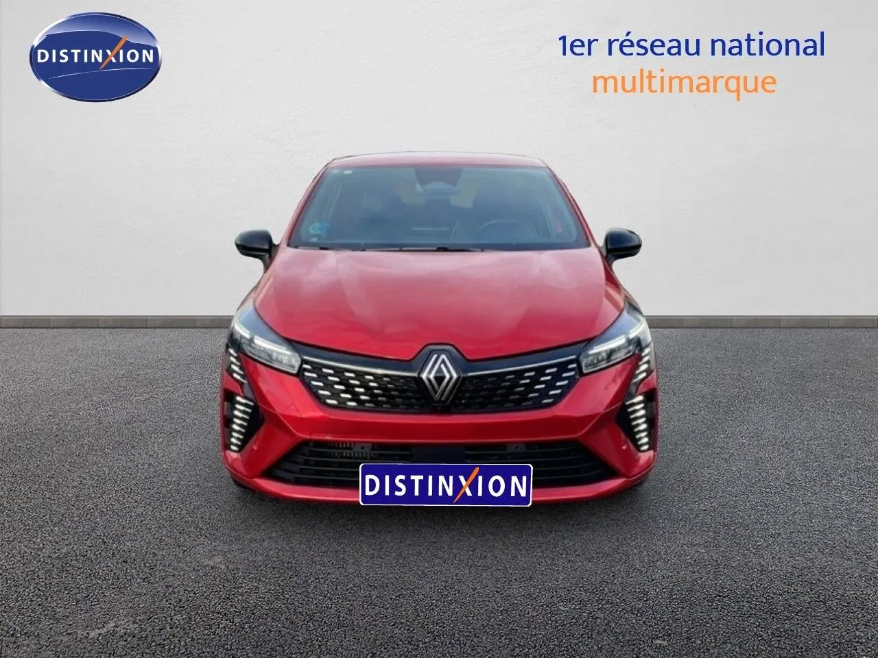 Vue frontale d'une Renault Clio 2025 rouge désir métal avec calandre noire et feux LED distinctifs allumés.