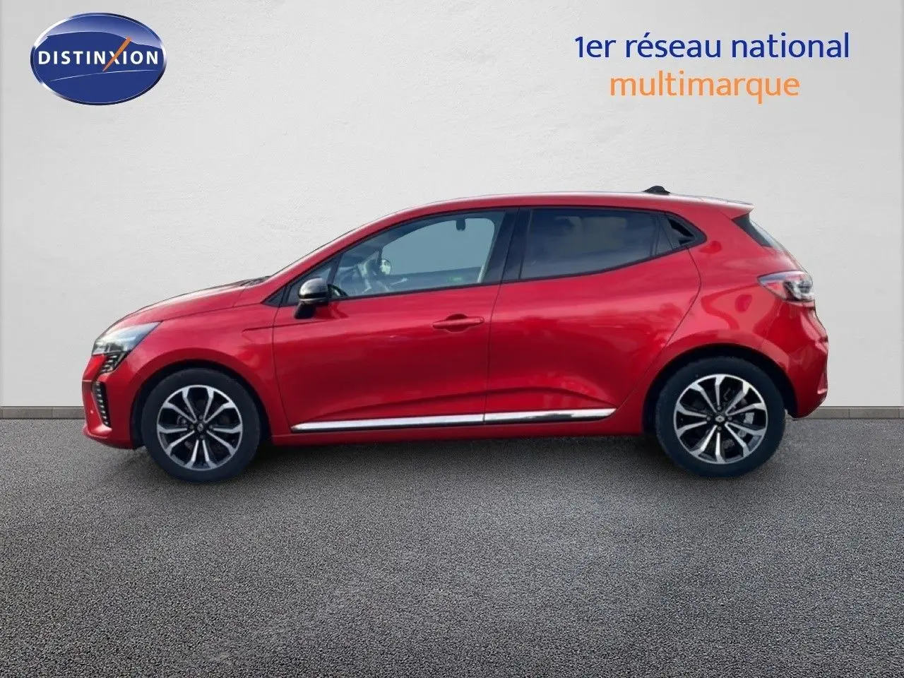 Profil droit d'une Renault Clio 2025 rouge désir métal avec jantes alliage et lignes chromées basses.