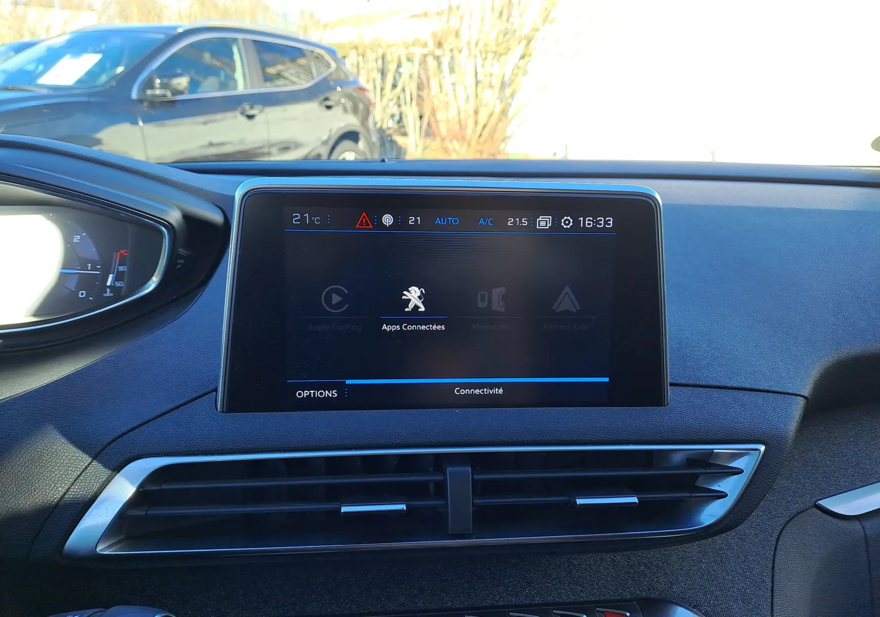 Vue intérieure centrée sur l'écran tactile du tableau de bord d'un Peugeot 5008 gris, affichant les options connectées.