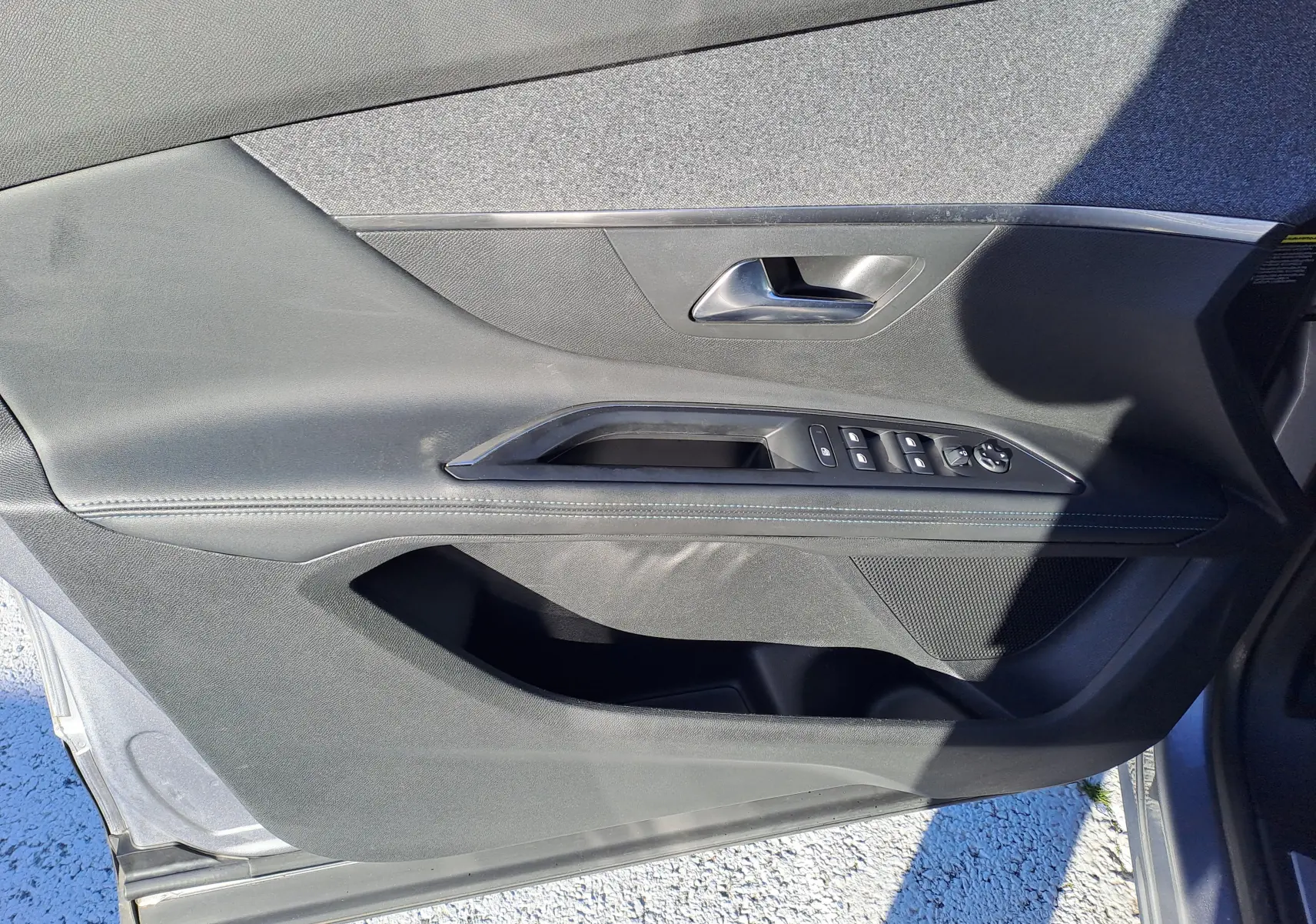 Vue rapprochée de la porte avant gauche grise du Peugeot 5008 2019, avec commandes de vitres et poignée intégrée.