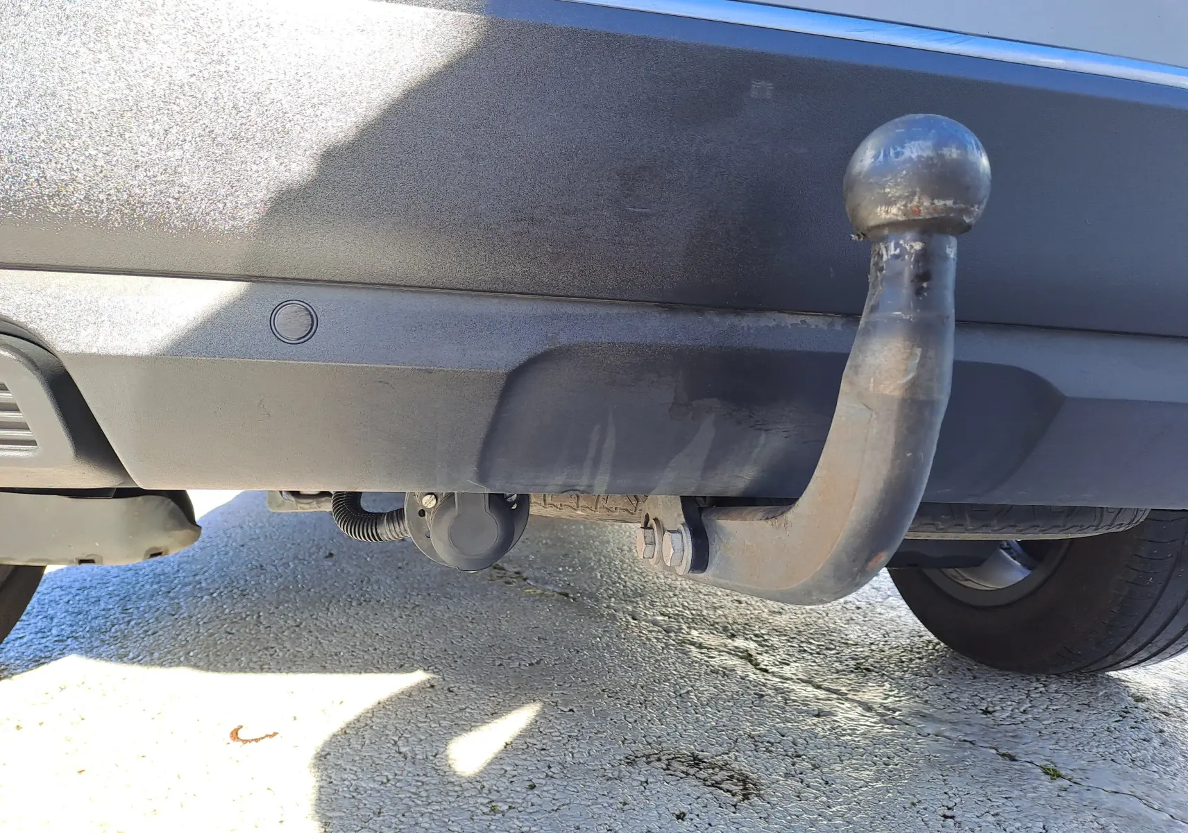 Gros plan sur l'attelage d'une Peugeot 5008 gris, vue arrière basse montrant la boule d'attelage rouillée.