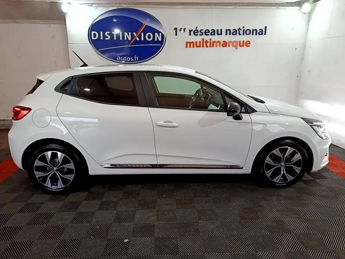 Profil droit d'une Renault Clio Business TCe 100 GPL blanche, avec jantes alliage et rétroviseurs noirs dans un showroom.
