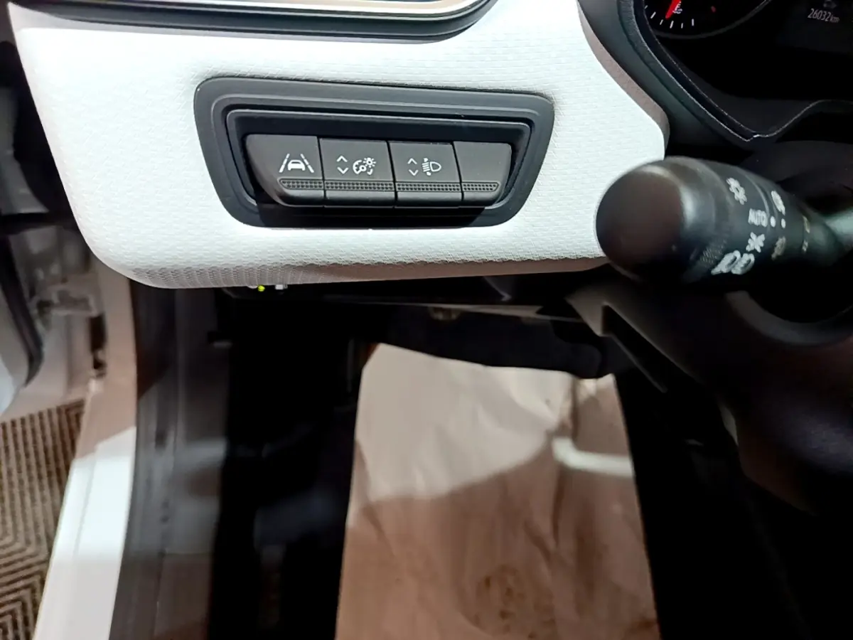 Gros plan sur les commandes d'assistance à la conduite sur tableau de bord blanc de la Renault Clio Business TCe 100 GPL 2023.