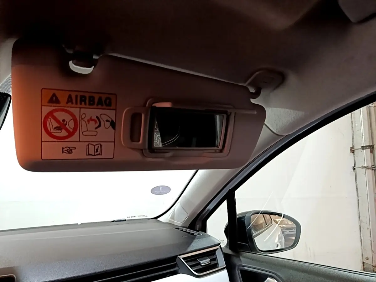 Vue intérieure côté passager de la Renault Clio Business blanche, avec pare-soleil et rétroviseur extérieur visible.