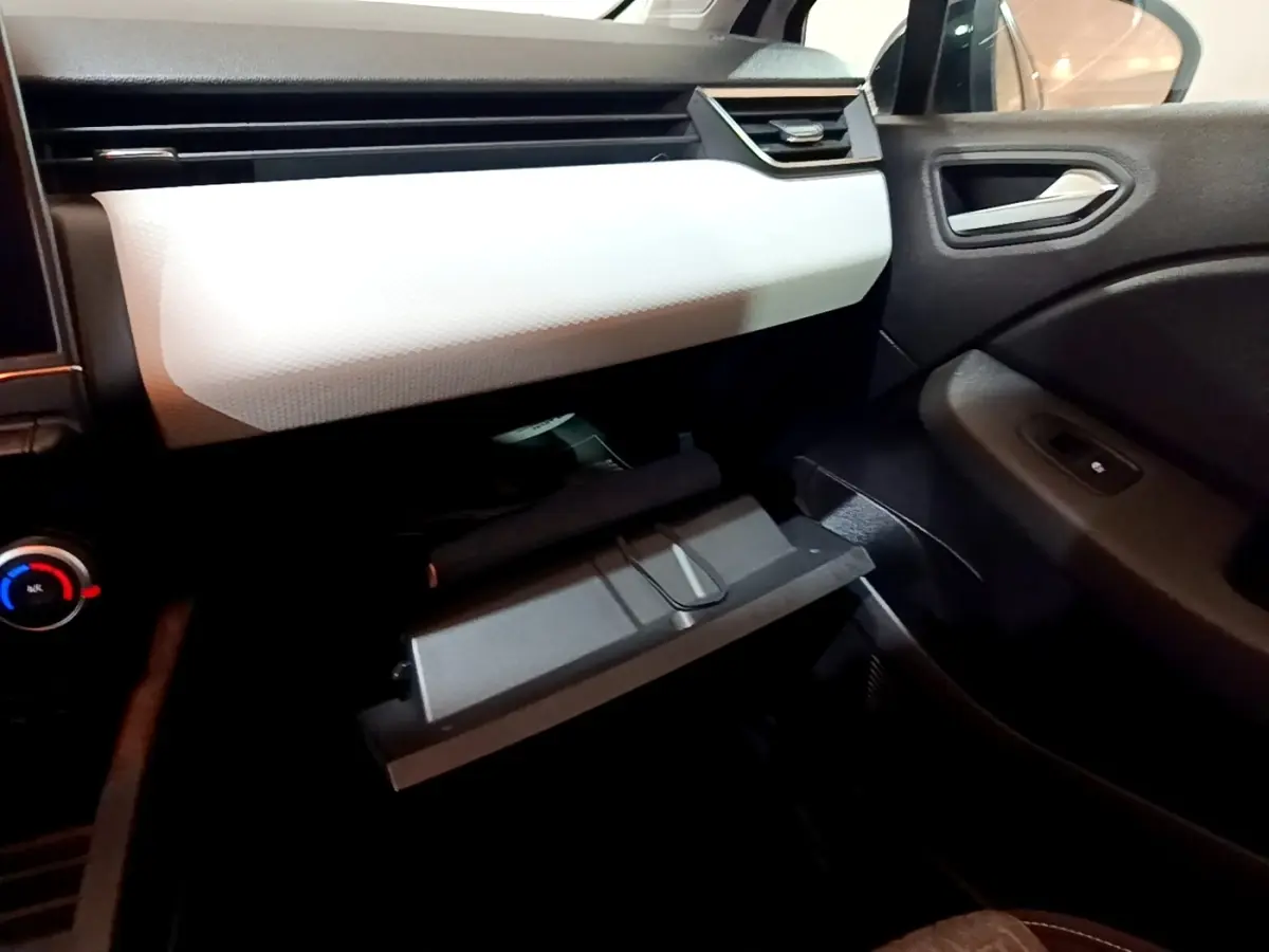 Intérieur côté passager de la Renault Clio Business blanc, avec boîte à gants ouverte et tableau de bord clair.