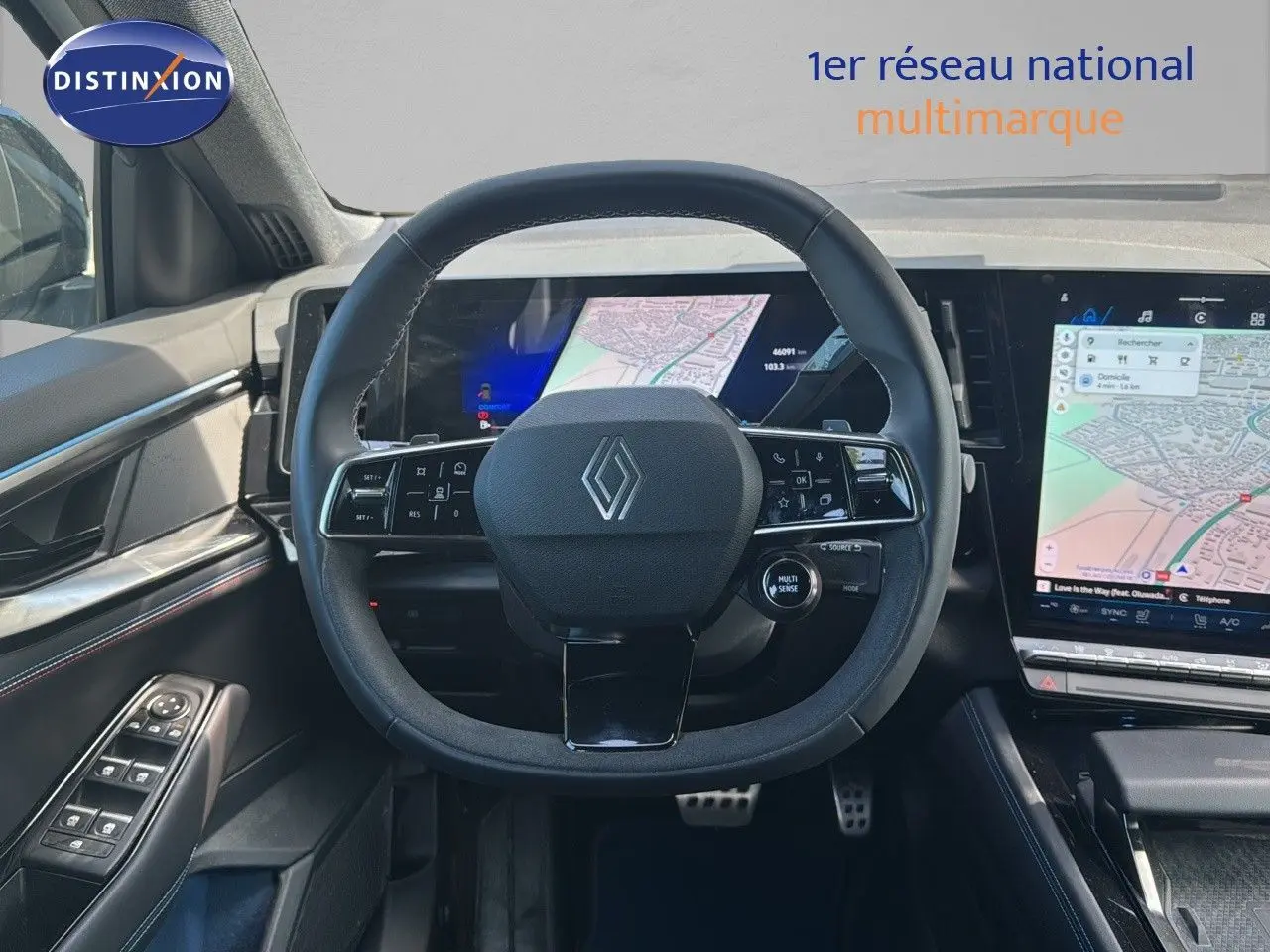 Vue intérieure centrée sur le volant Renault avec tableau de bord numérique et écran tactile affichant une carte GPS.