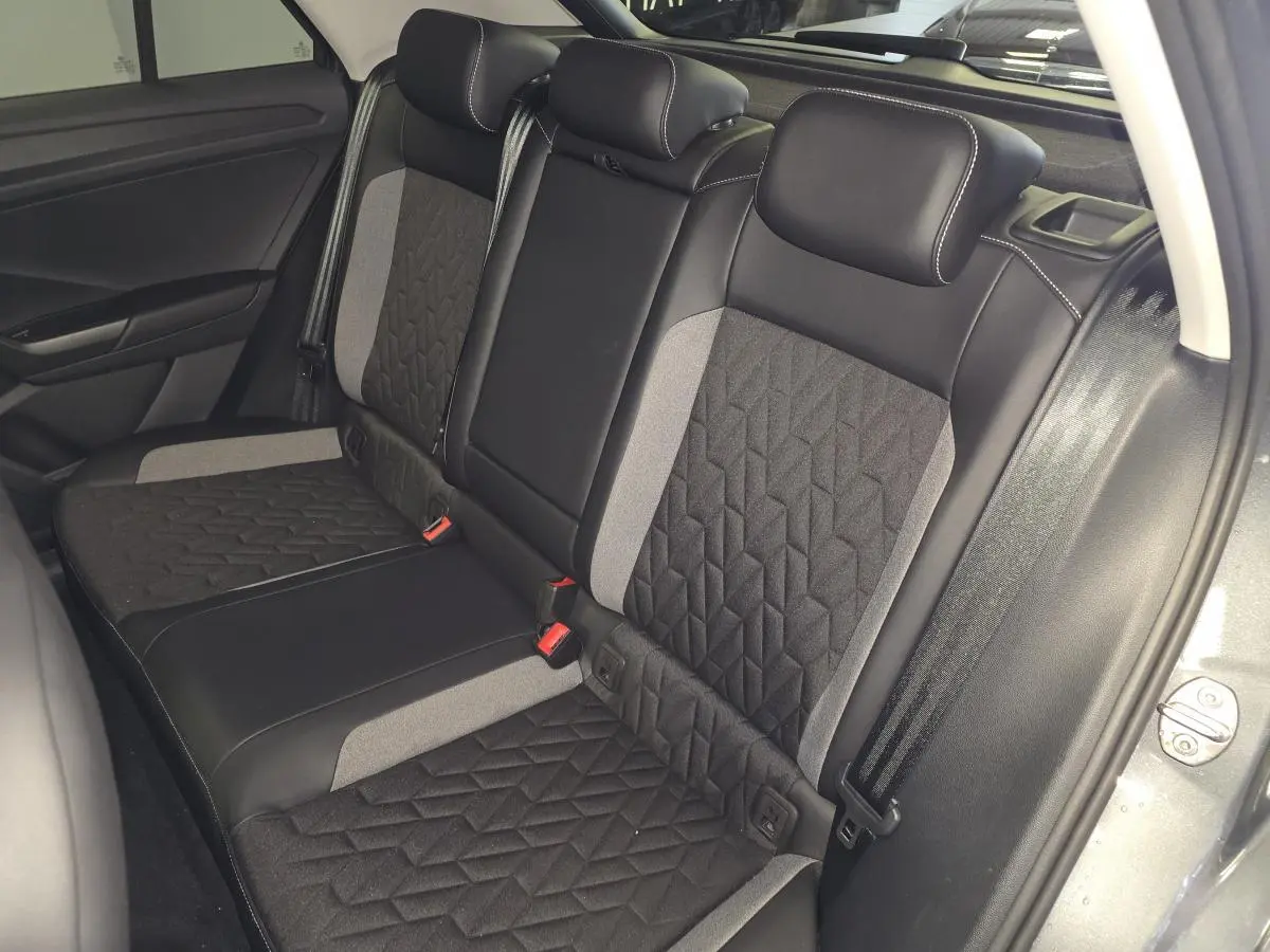 Vue intérieure côté droit des sièges arrière gris et noir du Volkswagen T-Roc 2025 avec ceintures de sécurité visibles.