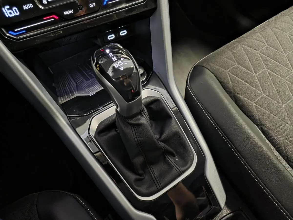 Gros plan sur la commande de boîte automatique et la console centrale du Volkswagen T-Roc 2025, sellerie tissu gris.