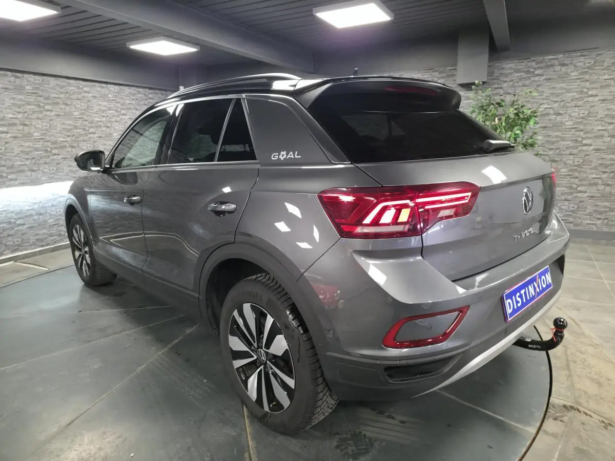 Volkswagen T-Roc gris en 3/4 arrière droit, toit noir avec logo GOAL et attelage démontable visible.