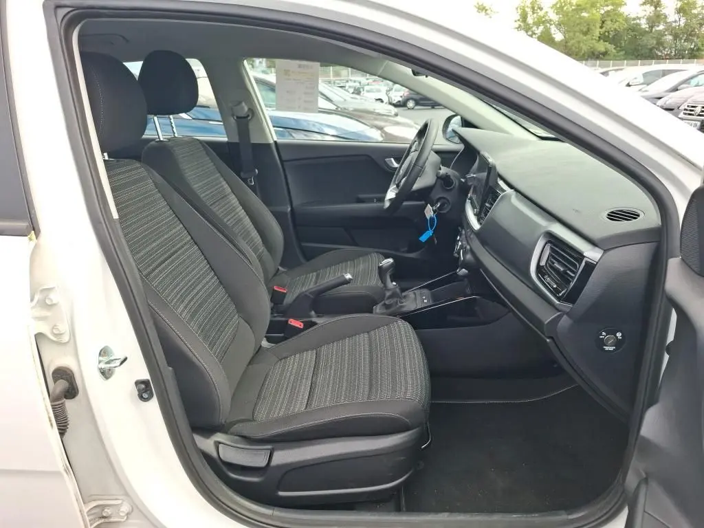 Vue intérieure côté conducteur du Kia Stonic blanc 2022, montrant les sièges avant et la console centrale avec boîte manuelle.
