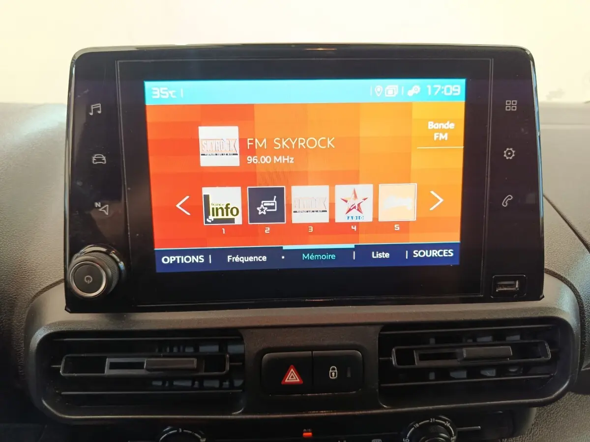 Écran tactile central du tableau de bord du Citroën Berlingo blanc, affichant une radio FM.