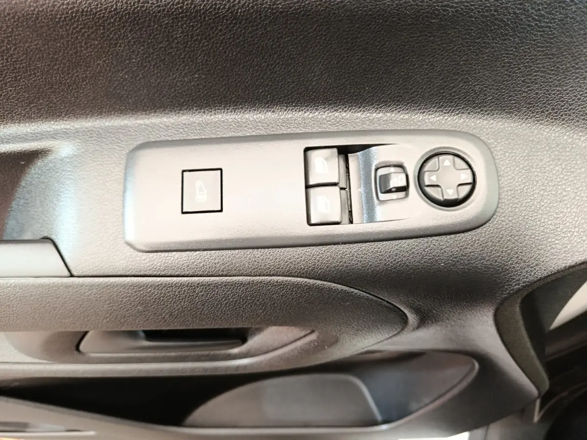 Vue rapprochée des commandes de lève-vitres et réglage des rétroviseurs sur la porte côté conducteur d’un Citroën Berlingo blanc.