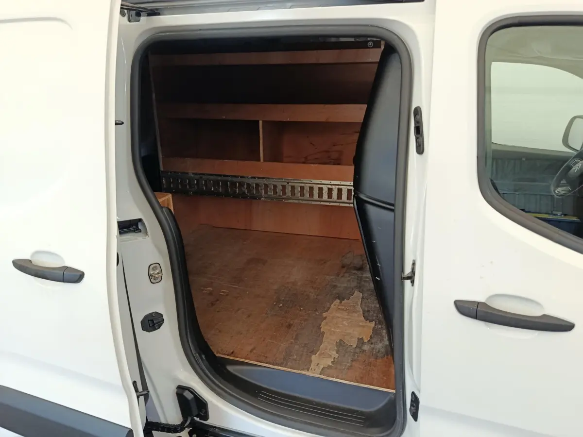 Vue latérale gauche sur la porte coulissante ouverte du Citroën Berlingo blanc, montrant l’espace de chargement en bois.