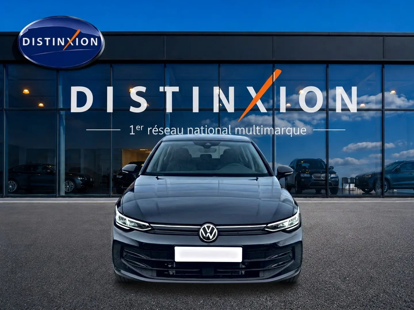 Vue frontale d'une Volkswagen Golf 1.5 ETSI Evo2 noire garée devant une vitrine avec logo Distinxion.